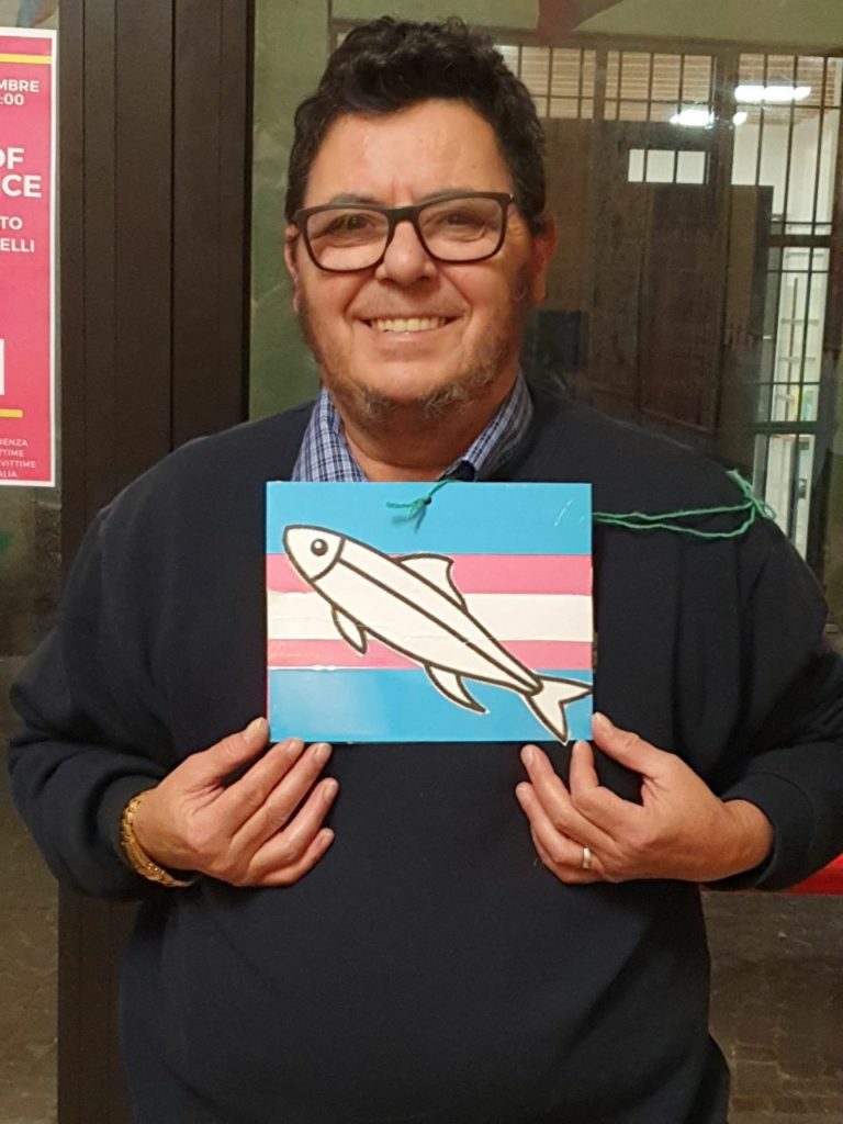 Andrea Di Martino con una "sardina" disgnata sulla bandiera trans